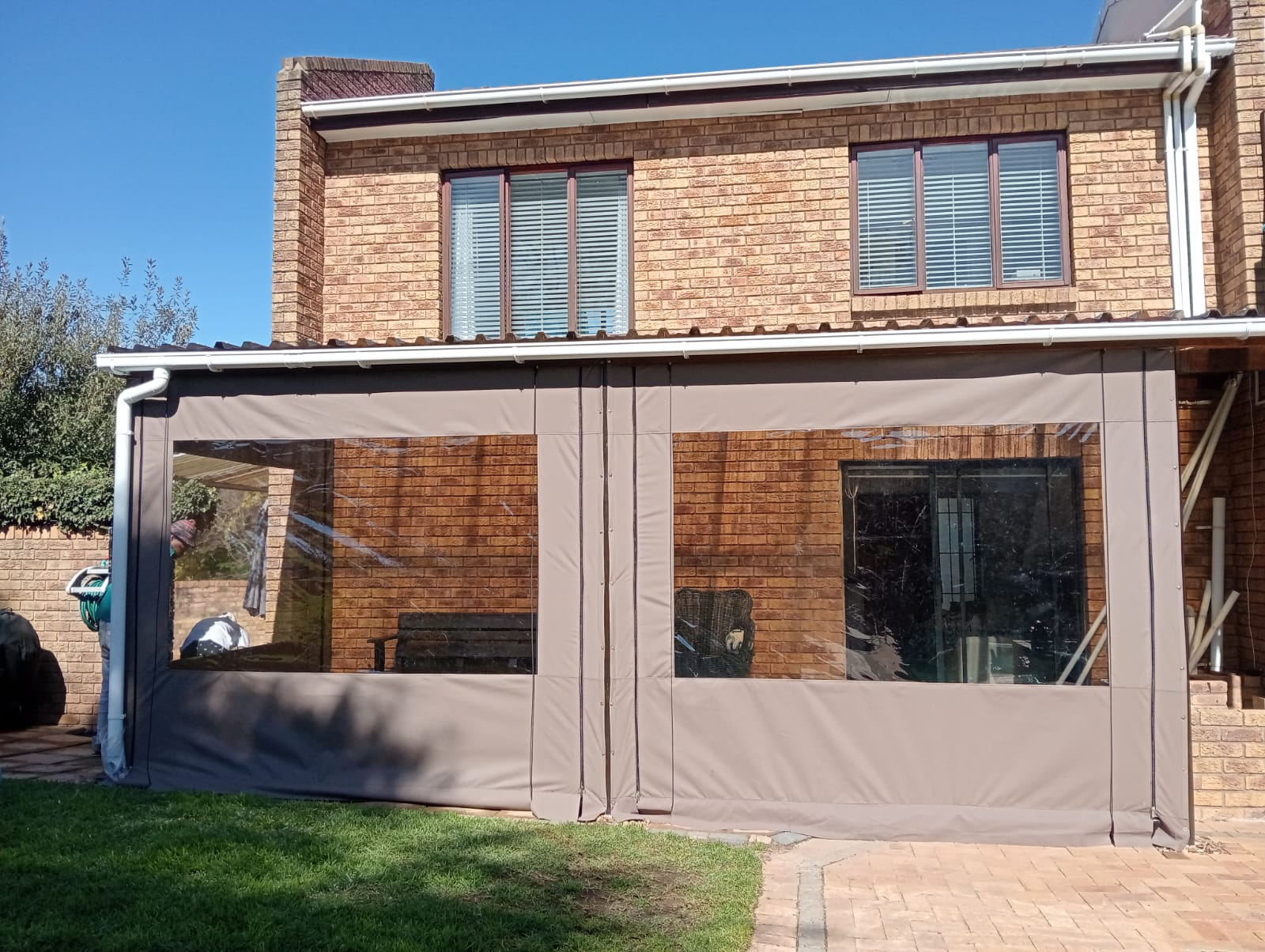 Clear outdoor blinds enclosing a brick patio